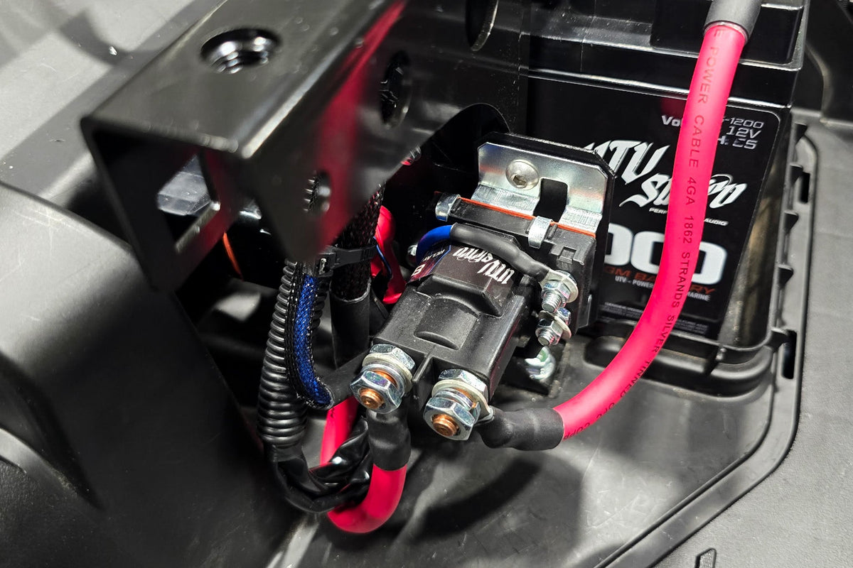 UTV Stereo relay mounted near a 12V battery with red power cables connected