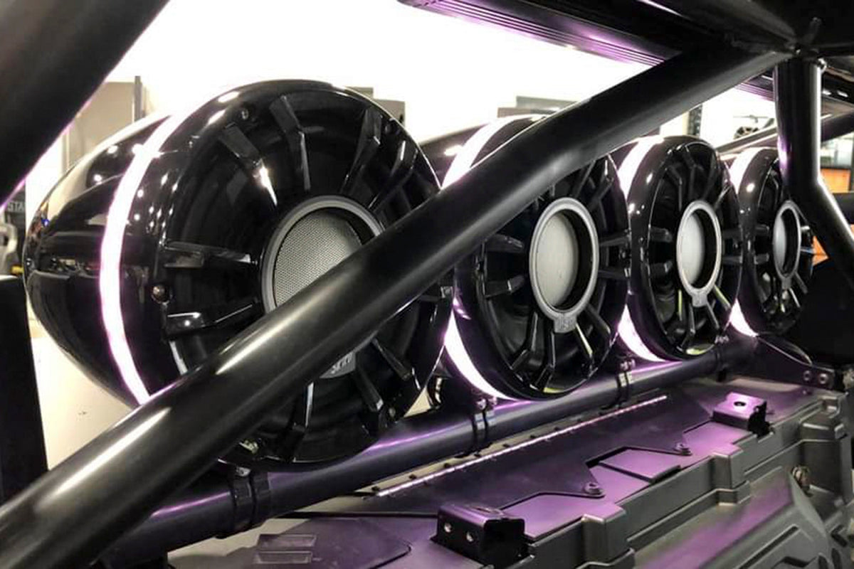 Four circular black marine speakers with LED rings mounted on a vehicle roll cage