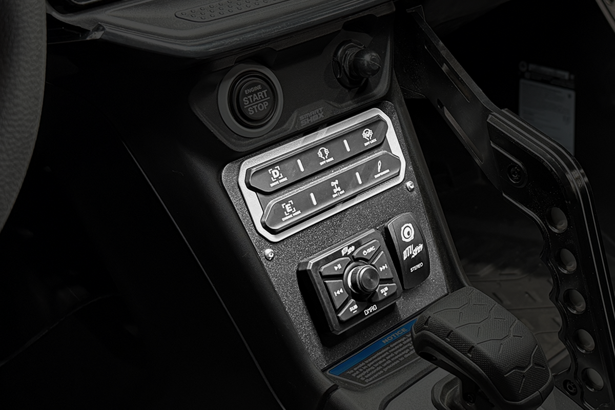 Center console controls with engine start button drive mode switches and stereo interface in a powersports vehicle