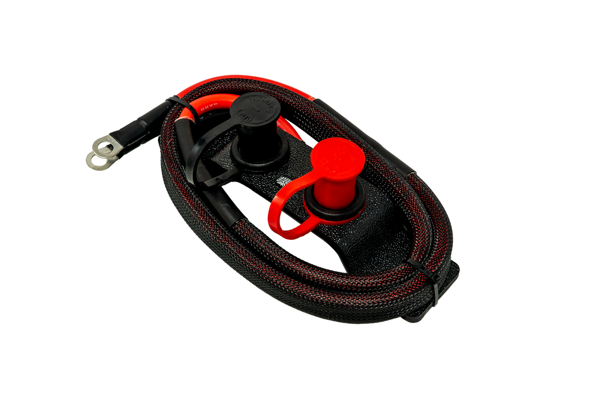 Remote battery charging posts with red and black protective caps and braided cables